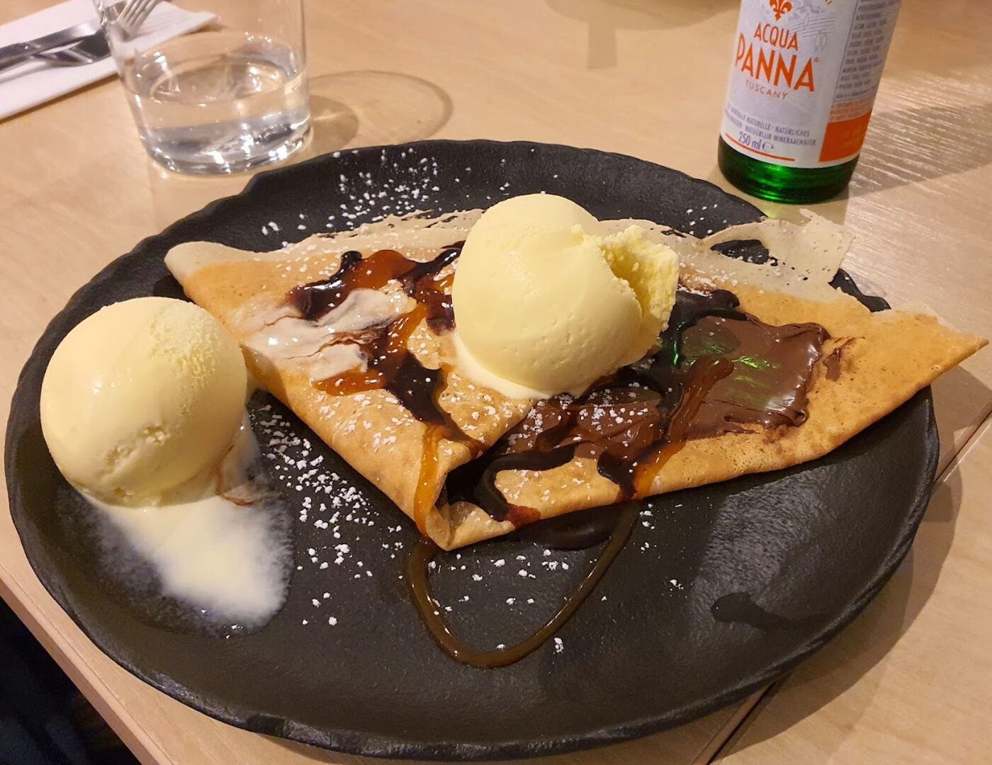 Een crêpe met chocolade en twee bollen vanille-ijs op een bord